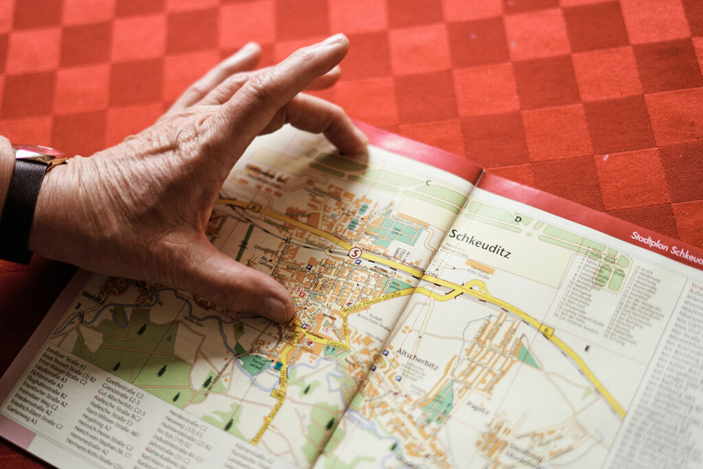 Die Hand eines alten Menschen zeigt auf einen Stadtplan von Schkeuditz